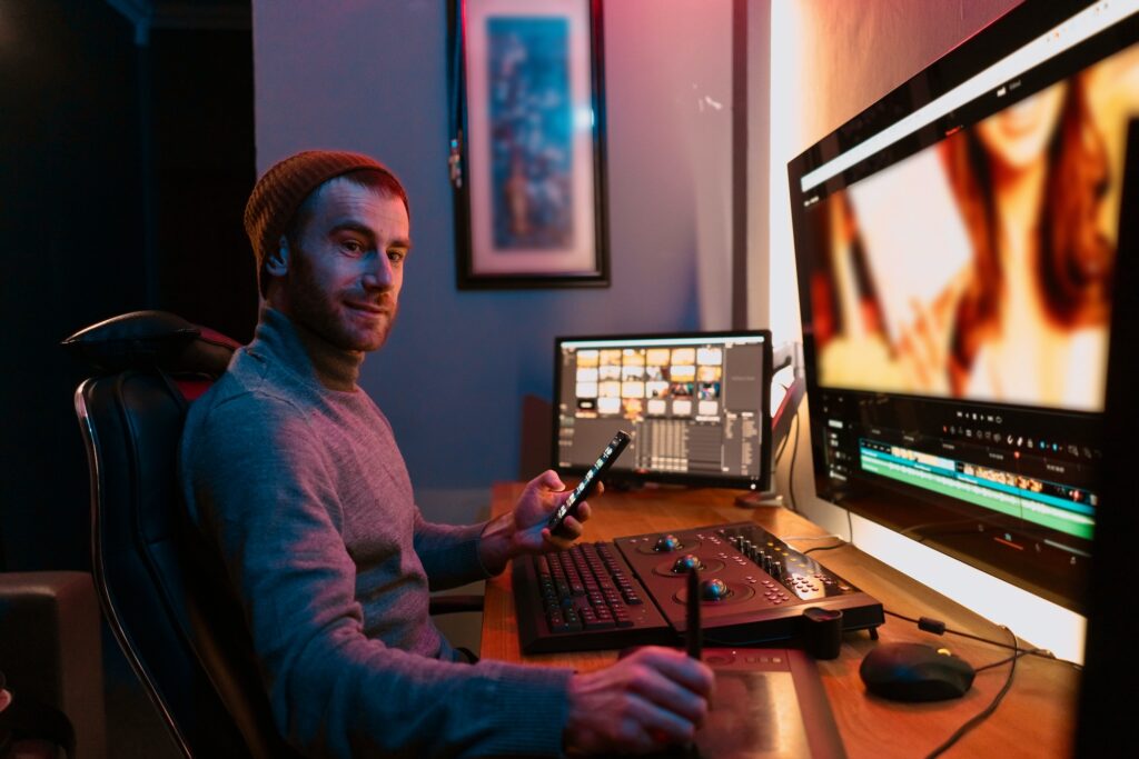 Male Video Editor sitting at his Computer using phone